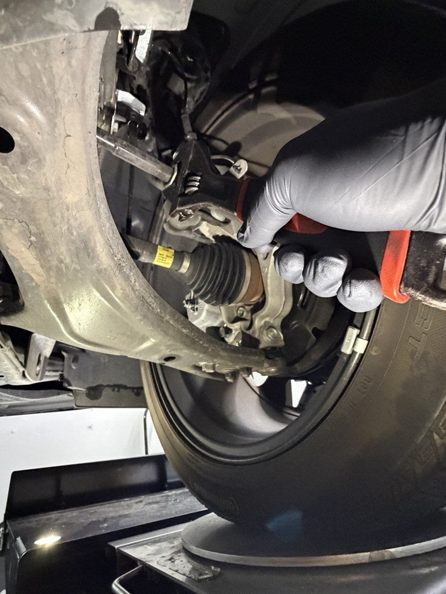 Technician using a wrench to make a Kia wheel alignment adjustment