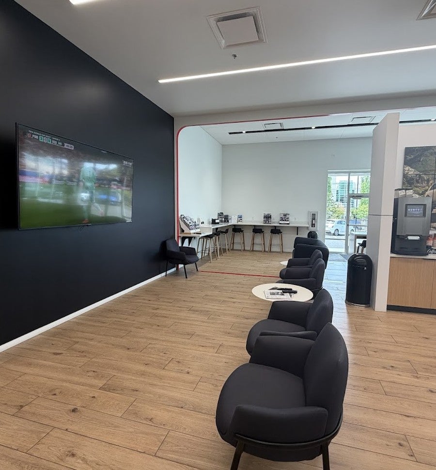Kia of Portland customer service lounge with seating, work counter, television, and coffee station